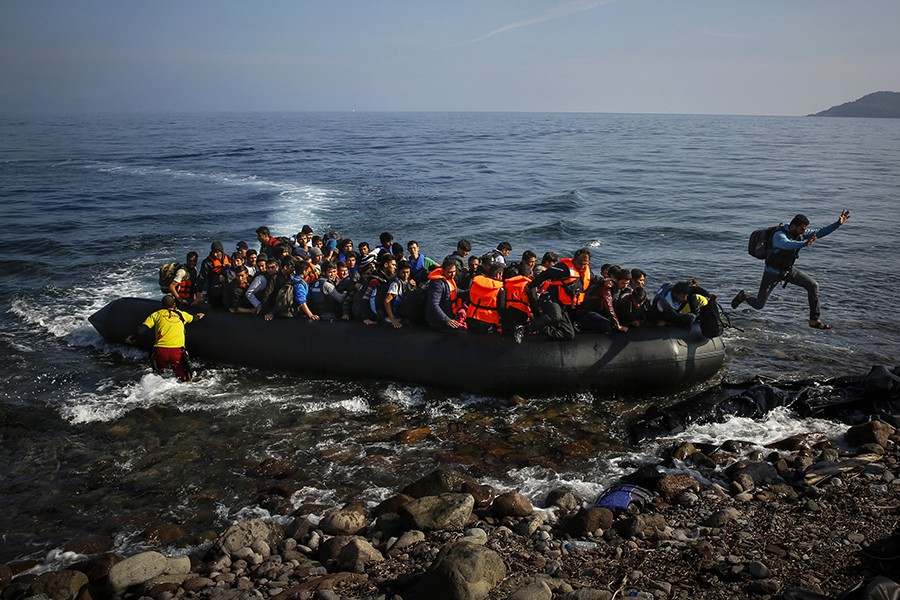 An Afghan migrant jumps off an overcrowded raft onto a beach at the Greek island of Lesbos (Yannis Behrakis, Thomson Reuters - October 19, 2015).