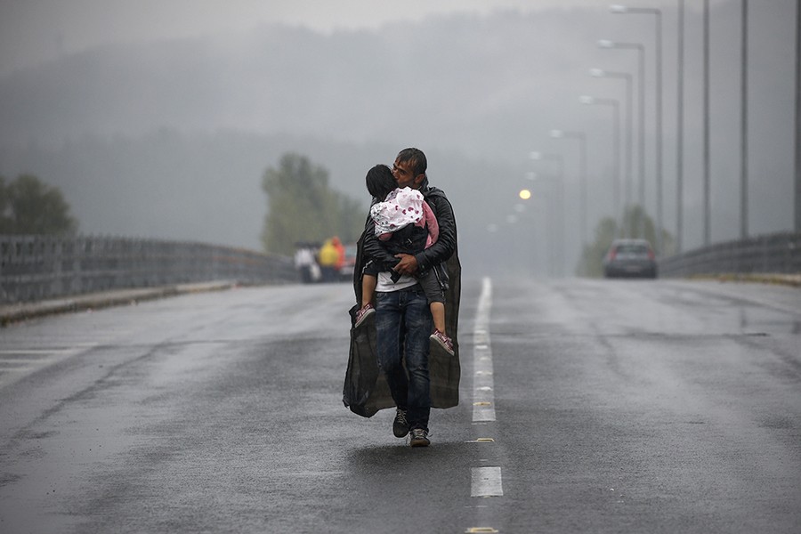 Syrian refugee kisses his daughter as he walks through a rainstorm towards Greece's border with Macedonia, near the Greek village of Idomeni (Yannis Behrakis, Thomson Reuters - September 10, 2015).