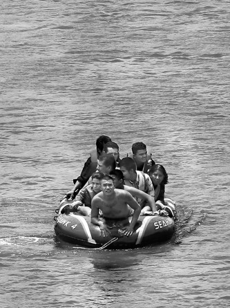 "Using an inflatable raft, coyotes, or smugglers, carry immigrants across by the international bridge on the Rio Grande in Roma, Tx., on June 24, 2014. According to law enforcement officials, higher risk smuggling operations have moved into Starr County in order to avoid the saturated border in Hidalgo, County. (Jerry Lara/San Antonio Express-News)