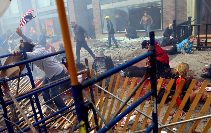 One of the heroes of the marathon bombings, Carlos Arredondo, scales over the barricades and starts breaking them down so first responders can get to the victims. (Photo by John Tlumacki, April 19, 2013)