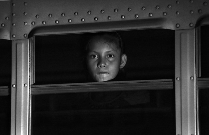 A young girl peers out a bus window waiting with other children to be taken to a shelter in San Pedro Sula, Honduras. Thirteen busses full of children and their families arrived overnight, at the Honduras Family and Children Shelter Center in San Pedro Sula carrying citizens of Honduras that were apprehended and deported from various cities in Mexico. Wednesday, June 25, 2014. (Bob Owen/San Antonio Express-News)