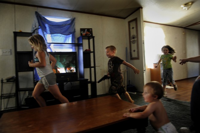 Greenville, Tenn.: While Jennifer Laughren is at work, children burn off energy in her trailer after eating lunch on the Lunch Express bus. Although the USDA program tries to offer a balanced meal, sometimes the high-sugar items offered, such as apple juice and cookies, put the children on a 'sugar high.' At center, Cameron Cutshaw, 5, holding a toy gun, chases his sister Dezaray White, 6, left. They are trailed by Gabriel Jones, 5, Jennifer Laughren's niece. Partly visible at right, Eric Jackson tries to c