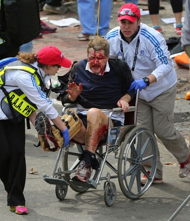 Eric Whalley is rushed from the scene by medical personnel. Quick action by first responders was credited with saving numerous lives. The medical team at the finish line, normally there to treat blisters and dehydration, assisted the critically injured within minutes of the blast. (Photo by David L. Ryan, April 16, 2013)