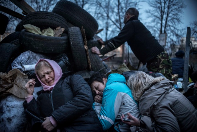 Feb. 21, 2014. Women take shelter from sniper fire at the barricades in Kiev. (Sergey Ponomarev for The New York Times)