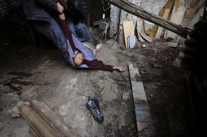 Syrian rebels lift a comrade who was shot by Army sniper fire after they prepared to attack a government held checkpoint in the Ain Tarma neighborhood of Damascus. (January 30, 2013)