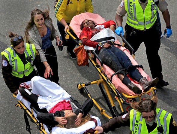 First responders rush Victoria McGrath and Mery Daniel (at right) from the scene, as Krystara Brassard runs after her injured friend. Daniel suffered serious injuries resulting in the amputation of her left leg. (Photo by David L. Ryan, April 16, 2013)