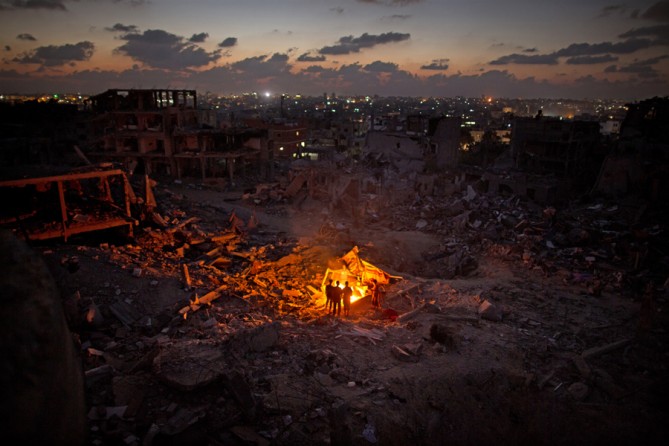 Aug. 28, 2014. Even after the fighting stopped, reconstruction was slow to nonexistent. At sundown, Gaza residents lit a fire in their destroyed neighborhood, Sha'af. (Wissam Nassar for The New York Times)