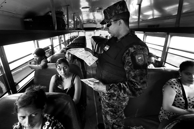 Captain Carlos Madrid of the Honduras Military Police checks the identification papers of a Honduran woman traveling with her two children to Guatemala, near the border town of Corinto, Honduras, on Friday, June 27, 2014. One child was born in Honduras and the other was born in Guatemala, and they were allowed to pass. (Bob Owen/San Antonio Express-News)