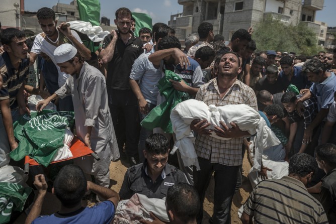 July 21, 2014. Palestinians mourn over the bodies of a family killed in an Israeli airstrike in southern Gaza. (Sergey Ponomarev for The New York Times)