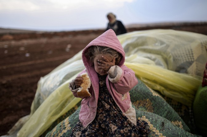 A Syrian Kurdish girl eats bread while she and her mother rest in Suruc in the Sanliurfa province, after crossing the border between Syria and Turkey, following several mortars attacks which hit both sides on October 2, 2014. (Bülent Kılıç/AFP)