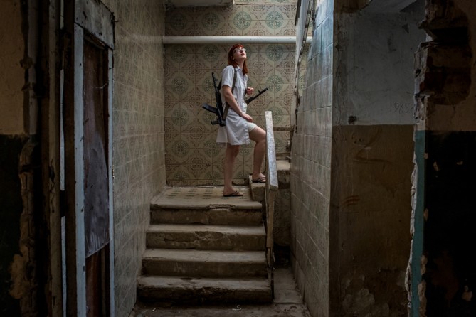 Aug. 24, 2014. A nurse holds rifles of pro-Russian rebels as they help move a patient from a hospital basement after an early-morning shelling in Donetsk, Ukraine. (Mauricio Lima for The New York Times)