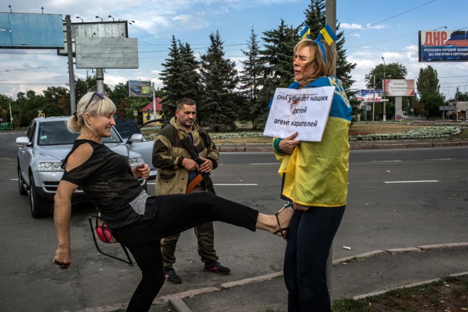 Aug. 25, 2014. Attacked and humiliated as a Ukrainian spy by pro-Russian rebels, Irina Dovgan, wrapped in a Ukrainian flag, was praying for death in this Donetsk traffic circle. Three days after the photo was made, she was released by a rebel commander who had been shamed into a rare act of mercy. (Mauricio Lima for The New York Times)