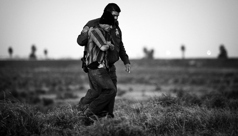 A Custom and Border Patrol officer walks with an undocumented immigrant from Guatemala who was found hiding in the tall grass just south of the border wall near Weslaco, Tx., on Thursday, Jan. 16, 2014. The immigrant voluntarily with the officer and is not cuffed. (Bob Owen/San Antonio Express-News)