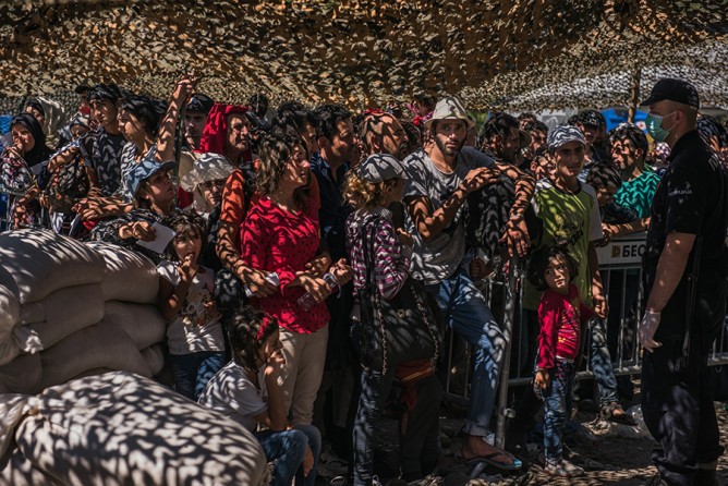 Refugees wait in line for documents at a processing center in Presevo, Serbia. Long lines of people stood in the blistering sun, begging guards to let them into the reception center. Refugees had to register to travel farther through Serbia. In Serbia, refugees could register to stay in the country for 72 hours, gaining the right to travel and even to stay in a hotel (Sergey Ponomarev, The New York Times - August 27, 2015).