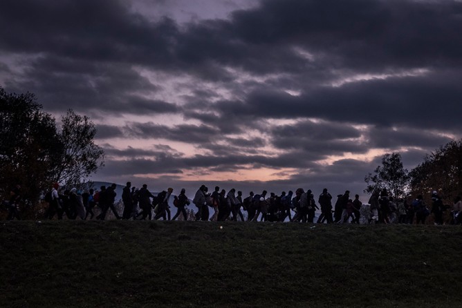 Migrants walking along a dike, escorted by Slovenian riot police, to a registration camp outside Dobova. Despite hopes that falling temperatures and treacherous seas would slow the tide of refugees, fresh fighting in Syria and growing fears of border closings drove more people to undertake the treacherous trek (Sergey Ponomarev, The New York Times - October 23, 2015).
