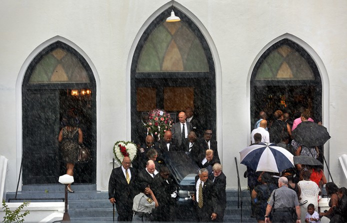 Pallbearers exit Emanuel AME Church carrying the casket of Cynthia Hurd while mourners for Susie Jackson and her nephew Tywanza Sanders file inside the church for their funerals in the lightning and heavy rain. The three were among nine worshippers to die in a mass shooting at the church on June 17. A procession of caskets and funerals filled the church for days (Grace Beahm, The Post and Courier - June 27, 2015).