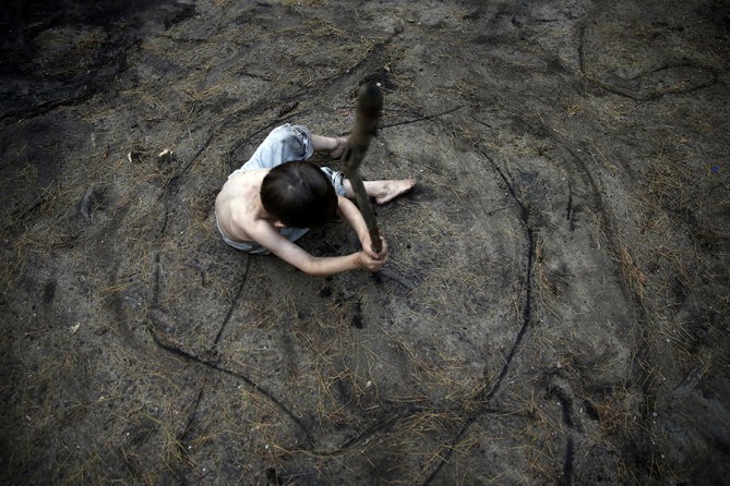 Having moved into their fourth campground of the summer, Gallagher sits in the center of a circle that his brother, Strider, has etched around him in the dirt. According to the state, living in a campground means they no longer have a house payment, because of this, their food stamps have been cut by a hundred dollars (Jessica Rinaldi, The Boston Globe).