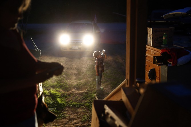 Gallagher cools off with a drink as Larry and Lanette scramble to pack by the light of their car headlights as the midnight eviction deadline inches closer. The landlord has cut the power and put locks on the electrical boxes in an attempt to force them off the property (Jessica Rinaldi, The Boston Globe).