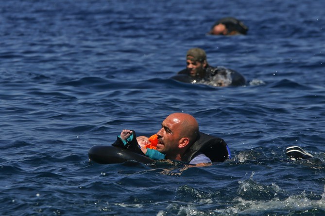 A Syrian refugee holding a baby in a life tube swims towards the shore after their dinghy deflated some 100m away before reaching the Greek island of Lesbos (Alkis Konstantinidis, Thomson Reuters - September 13, 2015). 