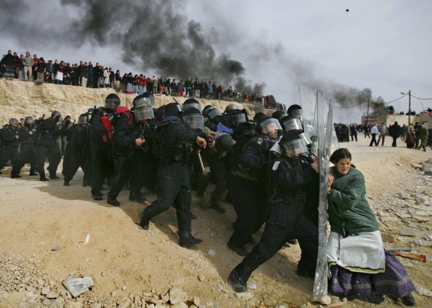 A lone Jewish settler challenges Israeli security officers during clashes that erupted as authorities cleared the West Bank settlement of Amona, east of the Palestinian town of Ramallah. Thousands of troops in riot gear and on horseback clashed with hundreds of stone-throwing Jewish settlers holed up in this illegal West Bank outpost after Israel's Supreme Court cleared the way of demolition of nine homes at the site. (February 1, 2006)
