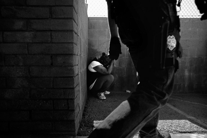 A woman waits to be questioned by authorities outside a suspected 'pill mill' in Sylmar, Calif., during an investigation by the Los Angeles County Sheriff's Department and other agencies. (December 31, 2012)