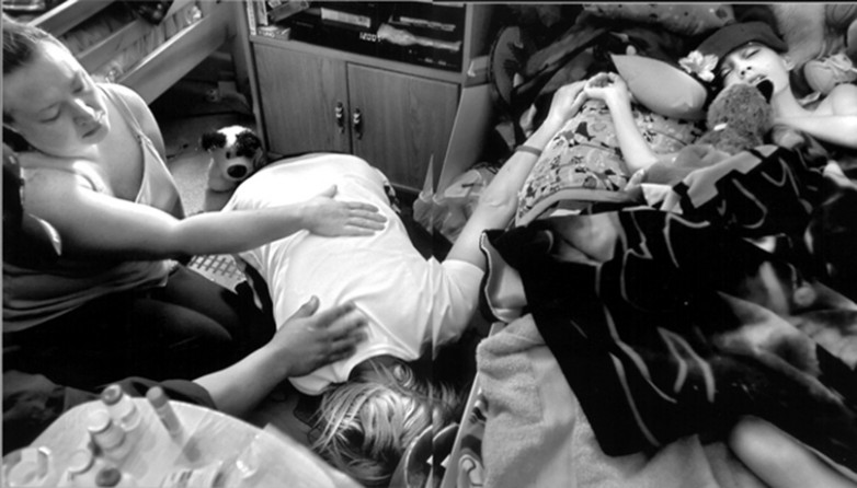 After placing a flower beside her son's head, a sobbing Cyndie drops to the floor on April 25, as her best friend, Kelly Whysong, left, and another friend, Nick Rocha, comfort her. Derek is too weak to acknowledge his mother's presence as she keeps a 24-hour vigil by his bed.