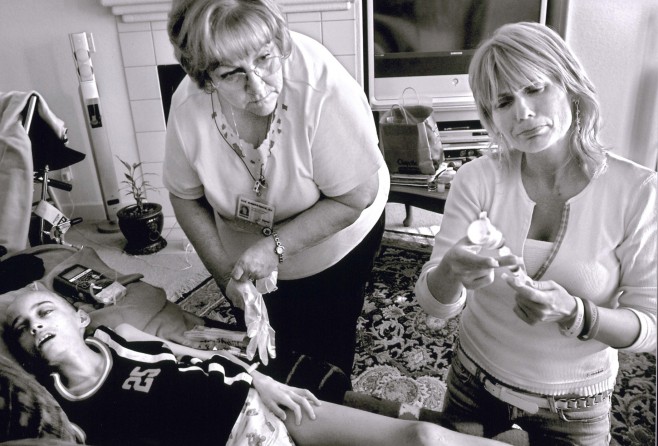 Cyndie French fights her emotions May 10, as she prepares to flush out Derek's catheter with saline solution before hospice nurse Sue Kirkpatrick, left, administers a sedative that will give the 11-year-old a peaceful death. "I know in my heart I've done everything I can," Cyndie says.