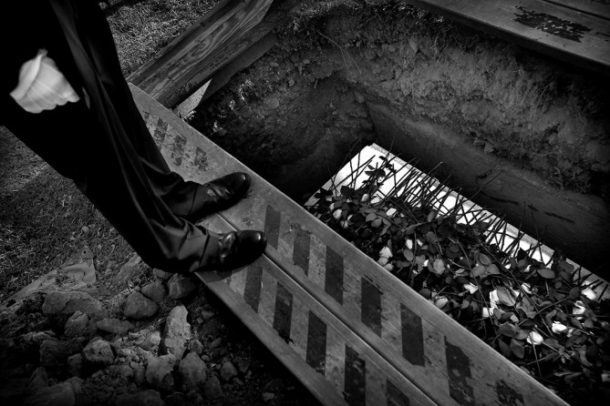 Two 16-year-old gang members have been charged as adults in connection with Melody Ross' killing. Tom Love Vinson and Daivion Davis are each charged with one count of murder and two counts of attempted murder after they allegedly opened fire into a crowd leaving Wilson High's homecoming game.  In this photo, Melody's uncle Che stands over her casket (Barbara Davidson, Los Angeles Times - December 29, 2010)