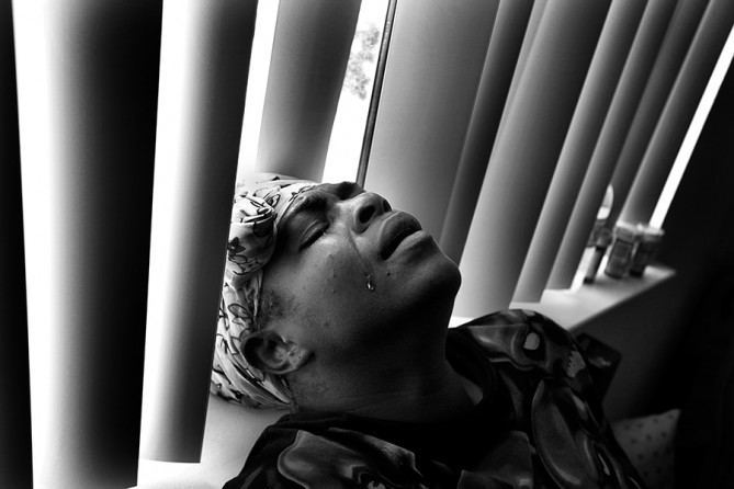 Rashaun Williams, 29, weeps with exhaustion after coming home for the first time after being shot and badly wounded by a stray bullet in South Los Angeles. Williams had recently moved from South L.A. to Lancaster to keep her 6-year-old daughter away from gang violence. But Williams returned to South Los Angeles to shop with her mother and was wounded during a gang-related drive-by shooting.  (Barbara Davidson, Los Angeles Times)