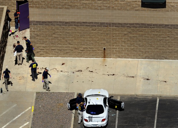 Investigators survey the scene at the Aurora Century 16 movie theater as the suspect's gun lays on the concrete outside the back door to theater 9. (Helen H. Richardson - July 21, 2012)