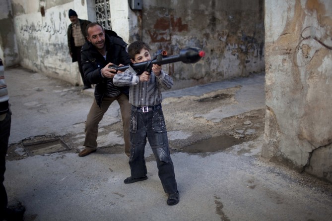 A man teaches Bilal, 11, how to use a toy rocket propelled grenade in Idlib, northern Syria, March 4, 2012. (Rodrigo Abd, Associated Press - March 4, 2012)