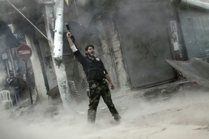 A rebel fighter gestures for victory after firing a shoulder-fired missile toward a building where Syrian troops loyal to President Bashar Assad were hiding as they attempted to gain terrain against the rebels during heavy clashes in the Jedida district of Aleppo, Syria, Nov. 4, 2012. (Narciso Contreras, Associated Press- November 4, 2012)