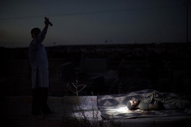 A man points a flashlight towards the body of a Syrian man killed by Syrian army shelling at a graveyard, in Aleppo, Syria, Oct. 13, 2012. (Manu Brabo, Associated Press - October 13, 2012)