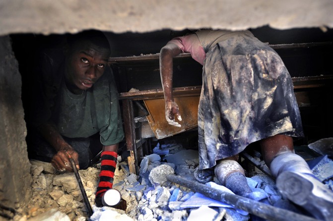 'Death of Innocence' A Haitian man tries to rescue a live teacher trapped amid the rubble of the devastating earthquake in Port-au-Prince as he crawls past a schoolgirl that perished at her desk when Ecole St. Gerard collapsed. (Carol Guzy, The Washington Post - January 15, 2010 )