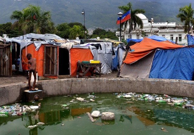 'Squalid Conditions' Months after the earthquake, a young boy washes in contaminated water at a tent camp near the severely damaged presidential palace looms in the background. The delays in reconstruction reflect bureaucratic red tape in donor nations and the complexity of rebuilding the Western Hemisphere's poorest country, which had little infrastructure, a snarled land-title system and a barely functioning government before the disaster. (Ricky Carioti, The Washington Post - August 22, 2010)