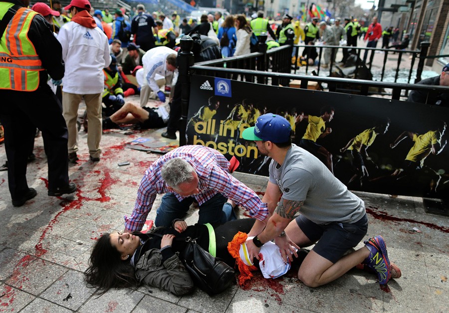 Matt Smith and Zack Mione use t-shirts and apply pressure to help save Sydney Corcoran, 17, on the sidewalk at the site of the first bomb. A piece of shrapnel the size of a cell phone severed her femoral artery, and she nearly bled to death. (Photo by John Tlumacki, April 16, 2013)