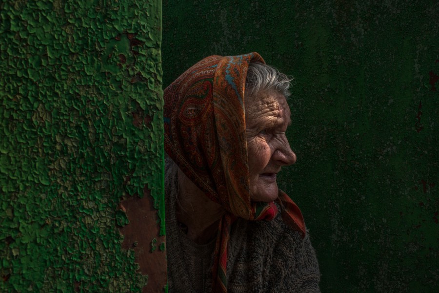 Aug. 1, 2014. A wary Ukrainian, Nadezda Ivanovna, 84, peers through the gate after collecting green apples from a tree near her home, on the outskirts of Slovyansk, a former pro-Russian rebel stronghold back in Ukrainian government control. (Mauricio Lima for The New York Times)