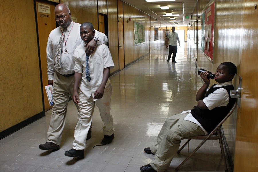 Sixth-grade teacher Peter Wilson escorts Dasni Wilson (no relation) to the principal's office for fighting on the playground as fifth-grader Chae' Adams sits in the hall for disrupting class. At the beginning of the school year fights commonly break out in class and during recess. (August 25, 2013)