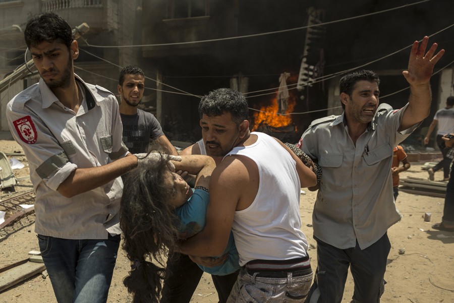 July 20, 2014. Palestinian emergency workers rescue a woman after an Israeli strike on a house in Rafah. The explosion took place next door to an apartment where photojournalists were staying. The photographer, Sergey Ponomarev, rushed to help victims, and, once rescuers arrived, photographed their work. (Sergey Ponomarev for The New York Times)