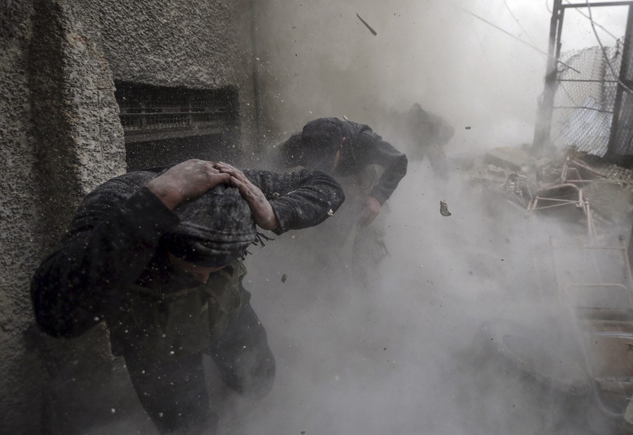 Syrian rebel fighters take cover from debris after a nearby wall was targeted by a tank shell from the Syrian Army during fighting in the Ain Tarma neighborhood of Damascus. (January 30, 2013)