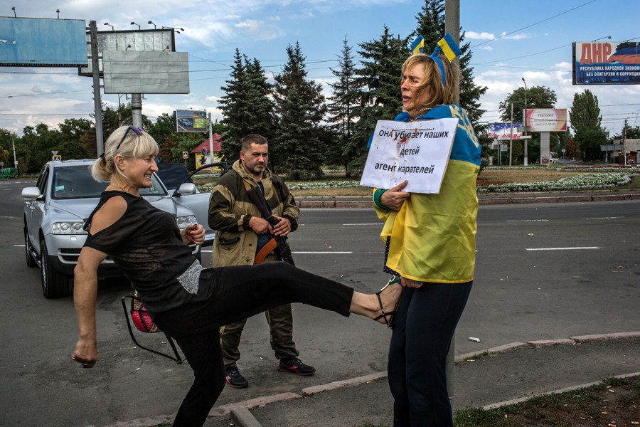 Aug. 25, 2014. Attacked and humiliated as a Ukrainian spy by pro-Russian rebels, Irina Dovgan, wrapped in a Ukrainian flag, was praying for death in this Donetsk traffic circle. Three days after the photo was made, she was released by a rebel commander who had been shamed into a rare act of mercy. (Mauricio Lima for The New York Times)