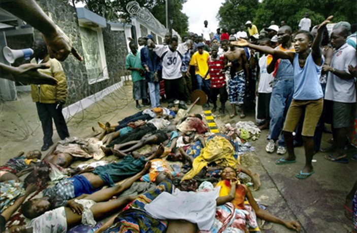 VOICES FOR THE DEAD: A crowd piles bodies outside the U.S. Embassy to emphasize their plea for American intervention. (Carolyn Cole)