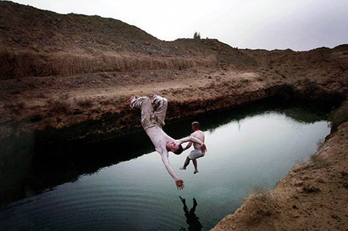 After weeks on their desert march to Baghdad, Spc. George Gillette and Spc. Robert Boucher take a chapter from boyhood and leap into the beckoning water of an irrigation pond. (David Leeson)