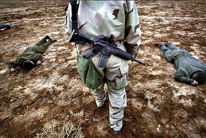 Walking past the bodies of Iraqi soldiers, a member of the 3rd Brigade Combat Team asks quitely, "Why do we do these things to one another?" (David Leeson)