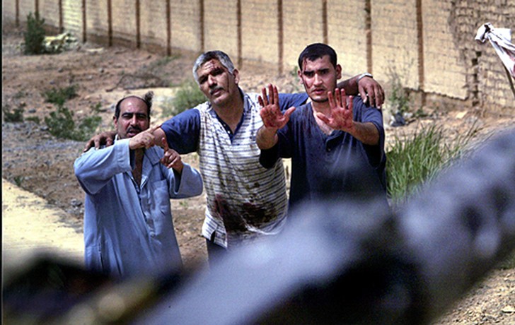 Wounded in an aerial bombing of Baghdad and seeking aid, Iraqi civilians raise their hands pleadingly toward advancing troops of the 3rd Infantry Division. (David Leeson)