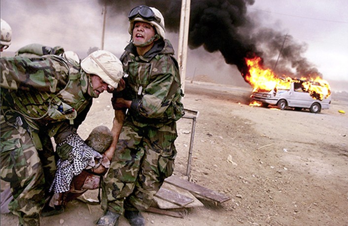 Risking their lives to save another, Lt. Jeffrey Goodman and Lance Cpl. Jorge Sanchez of the 2nd Tank Battalion drag a wounded civilian to safety after he was caught in the midst of battle on the road to Baghdad. (Cheryl Diaz Meyer)