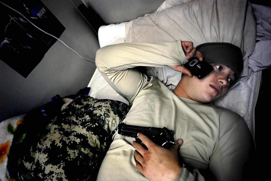 Fisher rests on his bed with his 9mm while calling a girlfriend back home Dec. 7, 2008.  A couple of weeks earlier, while communicating with friends on MySpace, he came to the realization that his on-again, off-again relationship with Kirsten Oliver was really over.  "It's one of those things, man," he said.  "You can’t really let it hit you.  Just continue with the mission... What the hell am I supposed to do?"  Soon after, he began calling a former girlfriend.  They talked about gettin