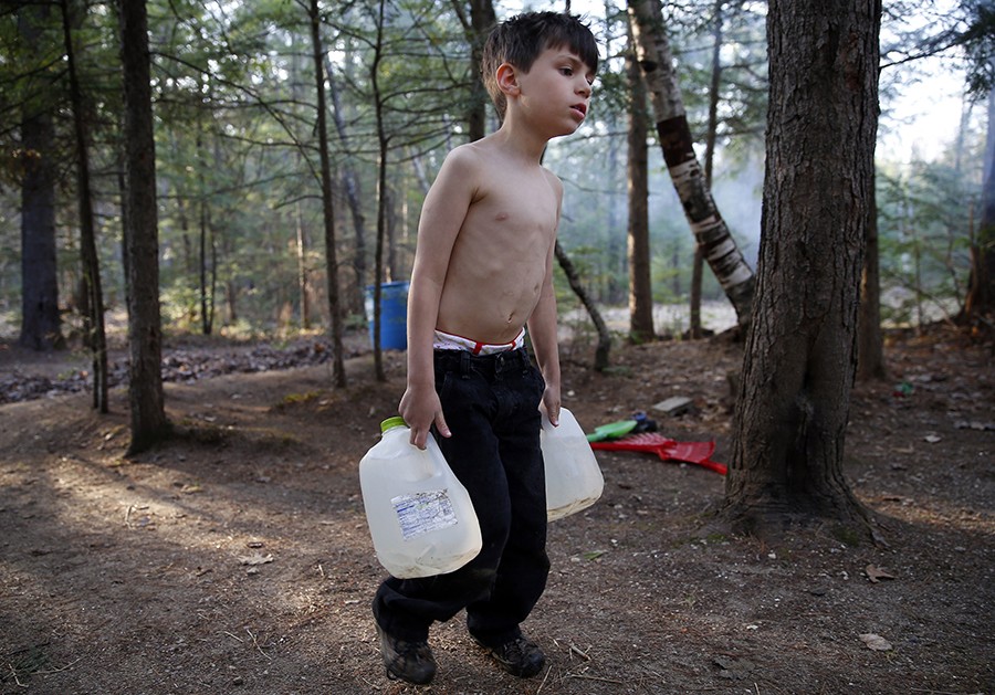 After moving into a campground, Strider struggles as he carries gallons of water filled from a spigot to the camper. Lanette will heat the water on a small stove to do the dishes and bathe the boys with a washcloth (Jessica Rinaldi, The Boston Globe).