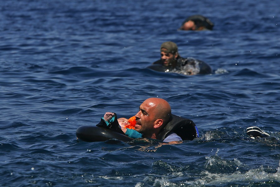 A Syrian refugee holding a baby in a life tube swims towards the shore after their dinghy deflated some 100m away before reaching the Greek island of Lesbos (Alkis Konstantinidis, Thomson Reuters - September 13, 2015). 