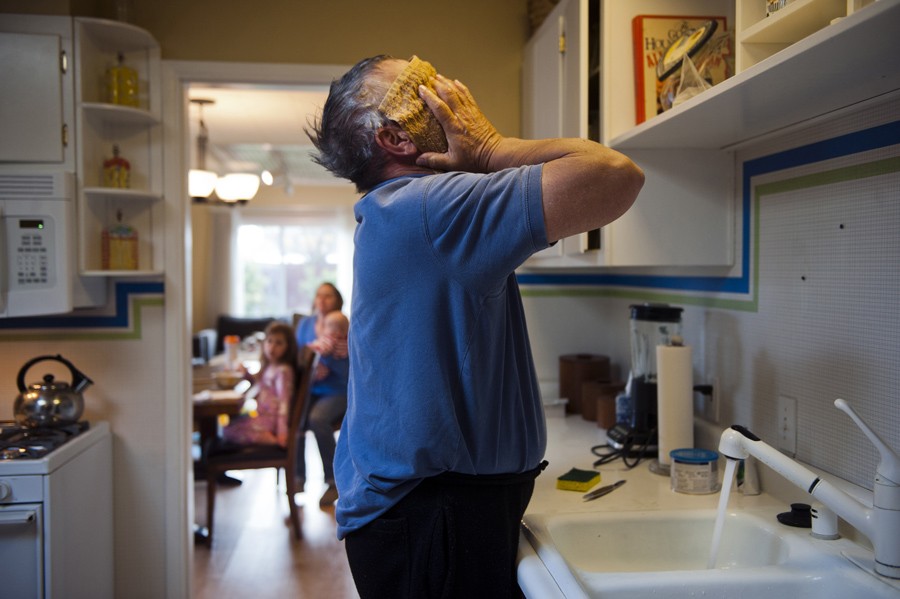 Always within eyesight of his grandchildren, Don Hatfield washes his face and hair in the kitchen sink so he can attend to Alex, 10 months, Ariel, 3, and Eva, 4, as the babysitter arrives.  (April 6, 2012)